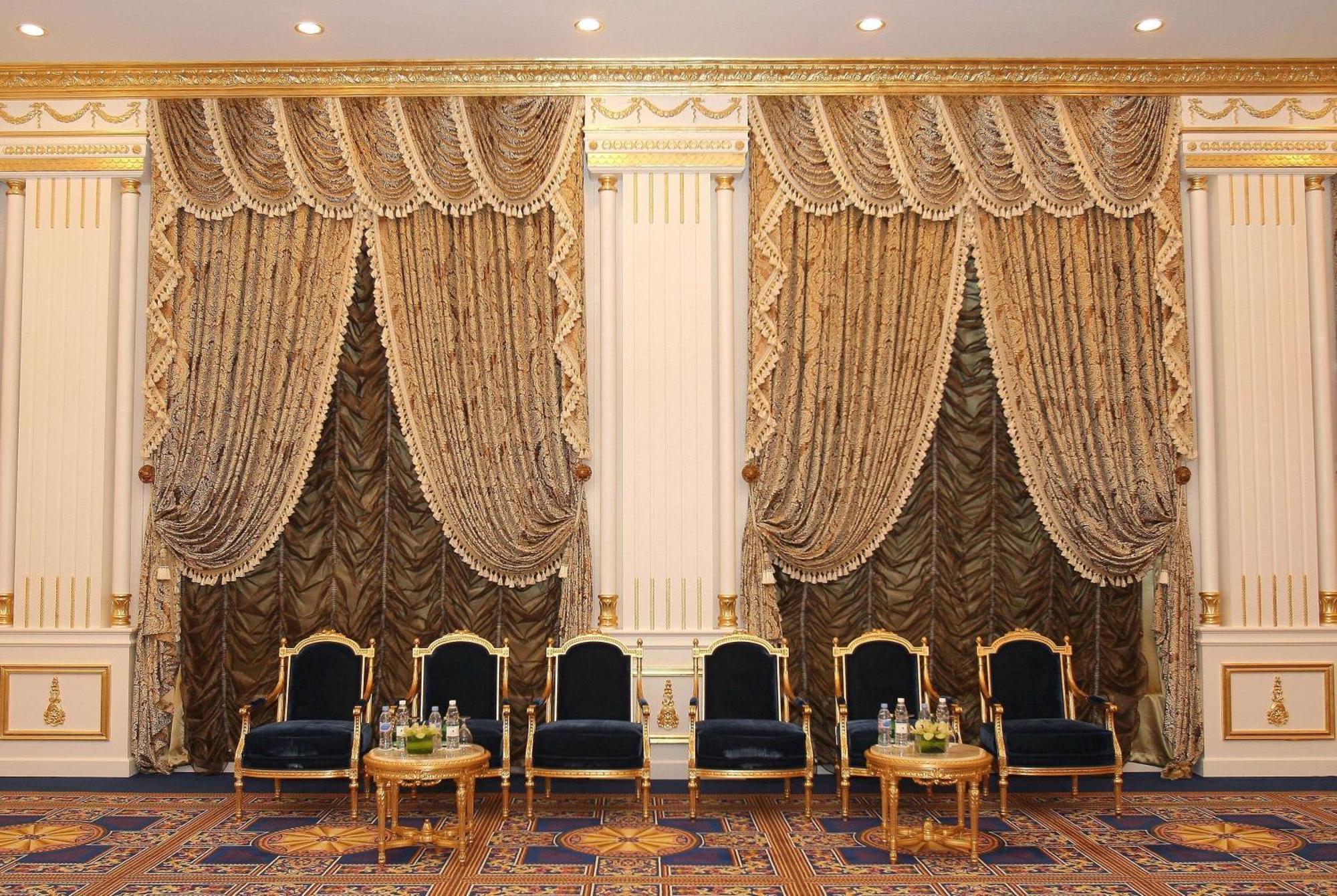 Grand Regency Doha, Trademark Collection By Wyndham Luaran gambar The photo shows an elegantly decorated interior space. There are two sets of opulent curtains on the walls, featuring rich fabrics with ornate designs and gold accents. The curtains are paired with decorative tiebacks. In front of the curtains, there