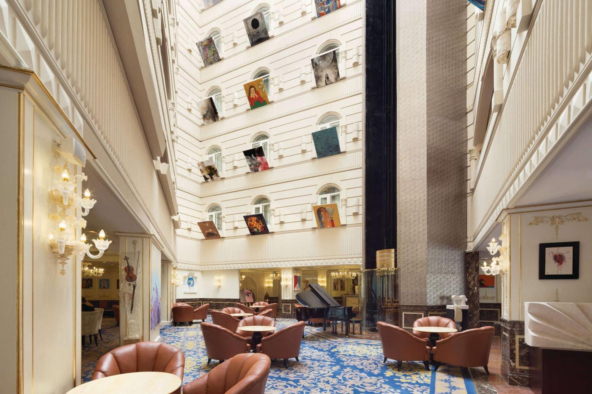 Grand Regency Doha, Trademark Collection By Wyndham Luaran gambar The photo depicts the interior of a spacious, upscale hotel lobby. The design features high ceilings and multiple levels, with large windows that create a bright and airy atmosphere. Elegant light fixtures adorn the walls, and the floor is covered wi