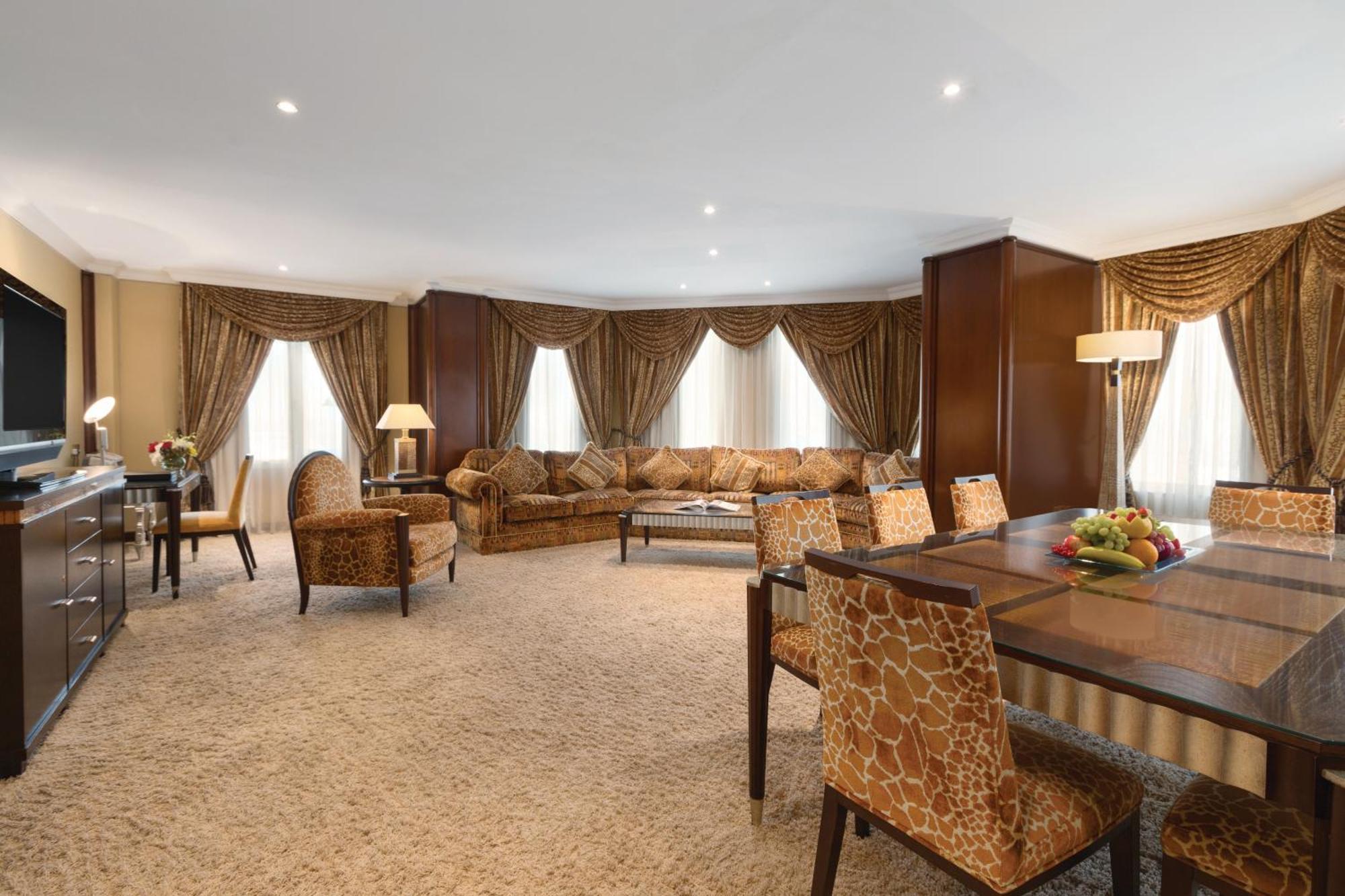 Grand Regency Doha, Trademark Collection By Wyndham Luaran gambar The photo shows a spacious and elegantly designed living area. There are large windows dressed with luxurious curtains, allowing natural light to fill the room. The seating arrangement features a comfortable sofa with various cushions and several sty