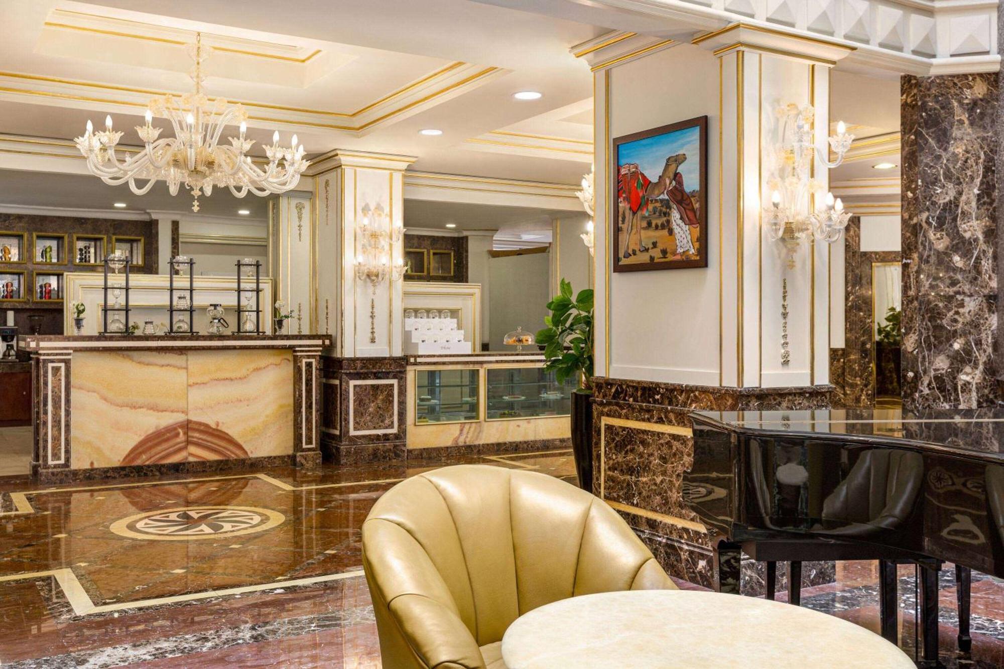 Grand Regency Doha, Trademark Collection By Wyndham Luaran gambar The photo depicts an elegant hotel lobby interior. It features a polished marble floor with intricate patterns. In the background, there is a reception desk made of marble and wood, with decorative elements and a glass display. On the walls, you can 